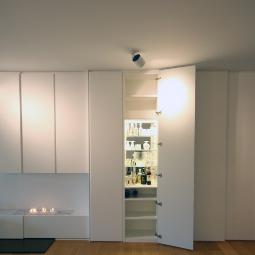 In een lange kastenwand zit onder andere deze barkast verstopt, waarbij de glazen legvlakken, een spiegel als rugwand gecombineerd met LED-verlichting alvast zorgen voor de juiste sfeer. Daarnaast is er heel wat opbergruimte om servies, tafellakens, glazen, … te bewaren zodat de bewoners alles meteen bij de hand hebben om een mooie gedekte tafel te presenteren bij etentjes. Vooral in de wintermaanden is het fijn als er een haard in de living brandt. Deze bio ethanol haard wou de eigenares graag laten inbouwen in de kast. En zo zorgden wij mee voor een gezelliger interieur. Kast-ID Antwerpen